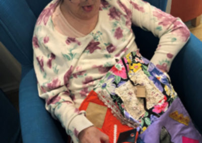 Bromley Park resident enjoying a colourful fidget blankets donated by the Beckenham Quilters