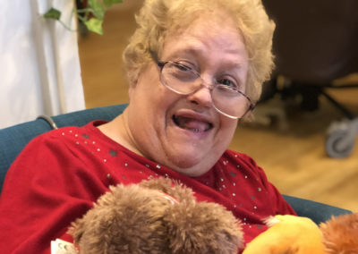 Bromley Park resident with cuddly toys smiling to camera