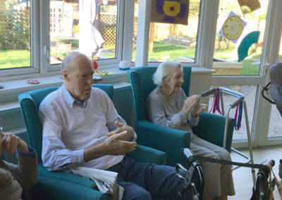 Seated residents listening to a singer in their lounge