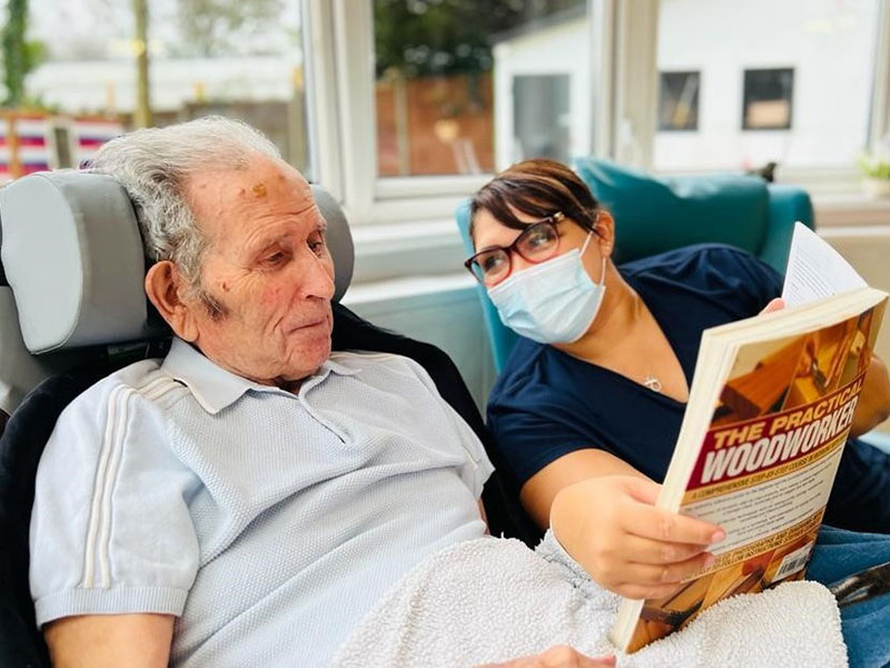 Crystal and Philip enjoying a woodworking book at Bromley Park Care Home